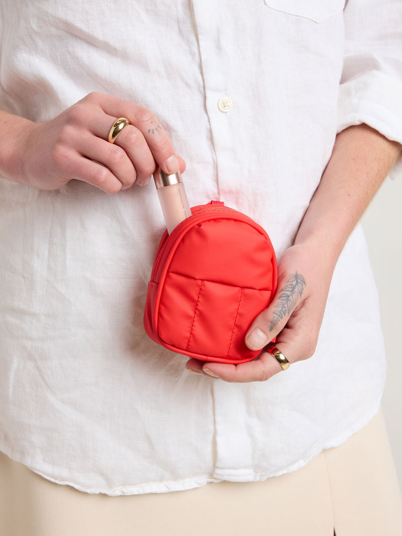 Person holding CALPAK Luka Backpack Zip Bag Charm in red Tomato