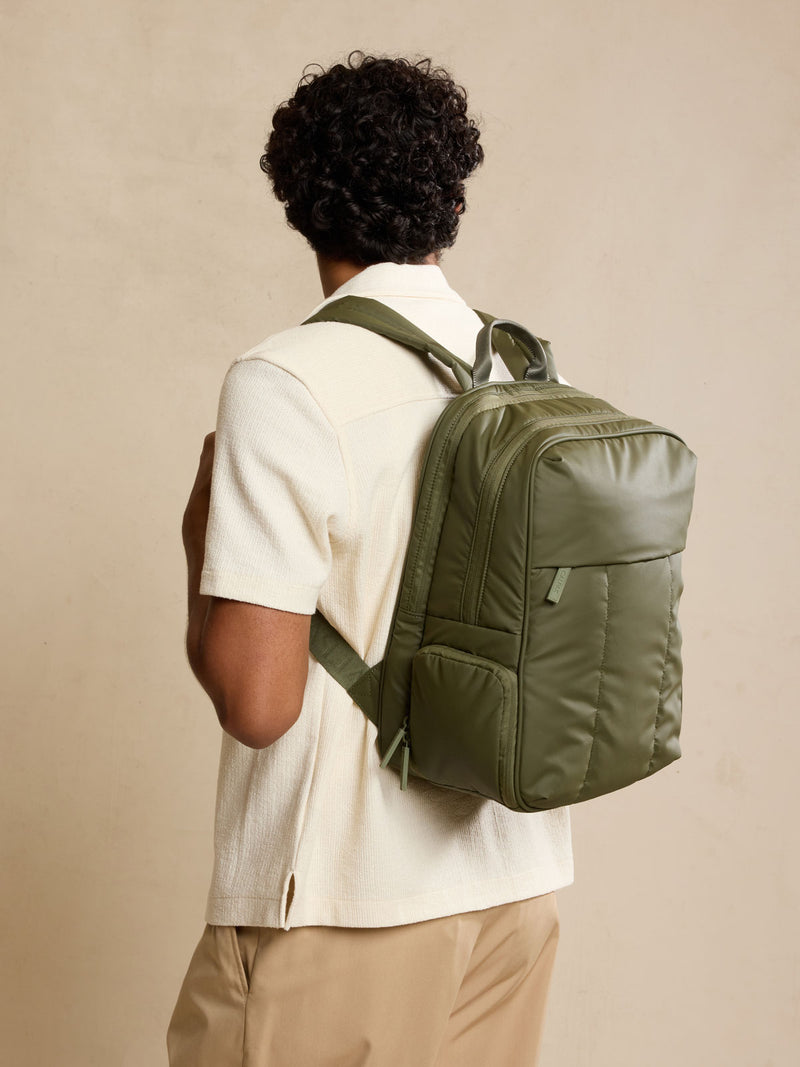 Model wearing CALPAK Luka 15in Laptop Backpack in dark green Pine