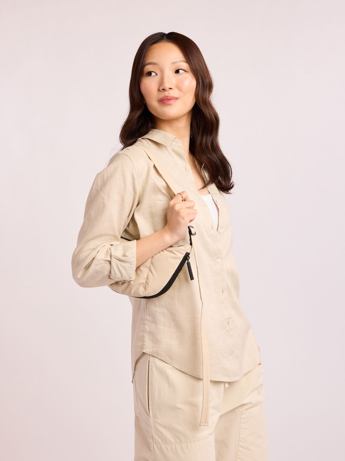 Model with beige outfit wearing CALPAK Luka Crescent Bag in beige off white Oatmeal; CBL2601-OATMEAL