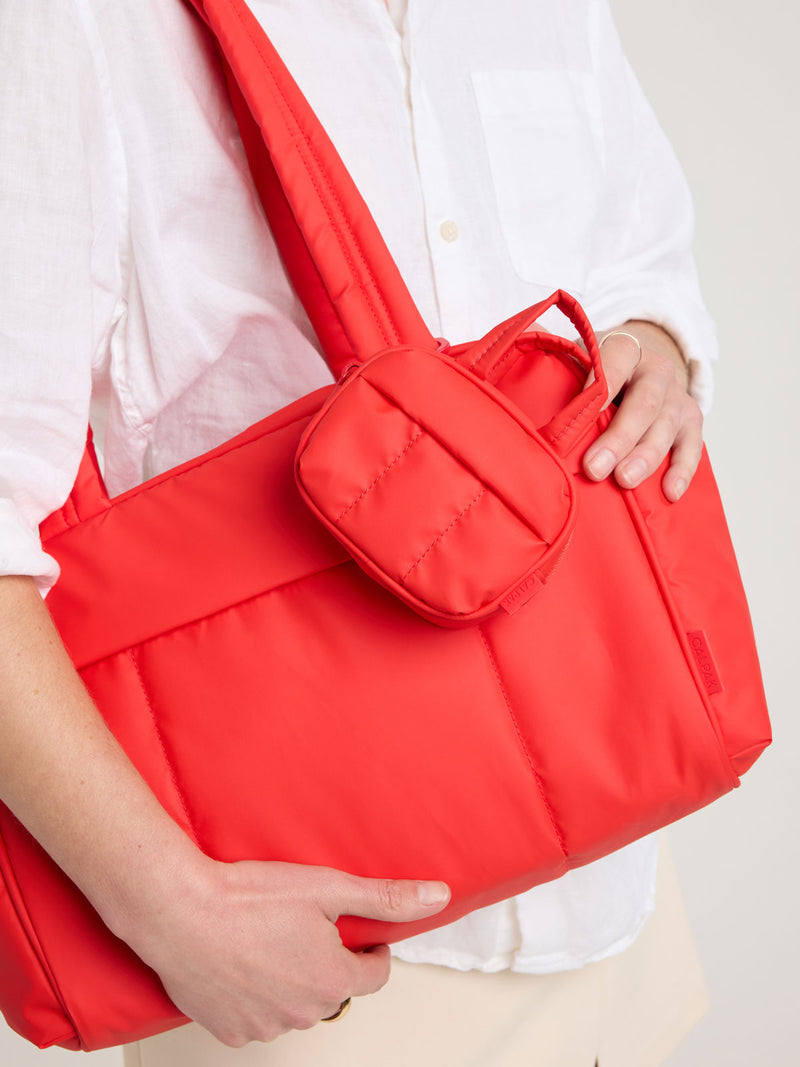 Person with CALPAK Luka Duffel Zip Bag Charm in red Tomato