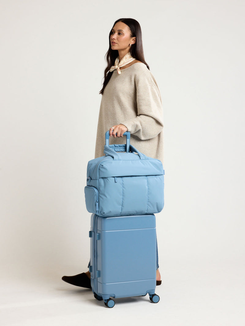 Woman with CALPAK Luka Duffel in light blue French Blue