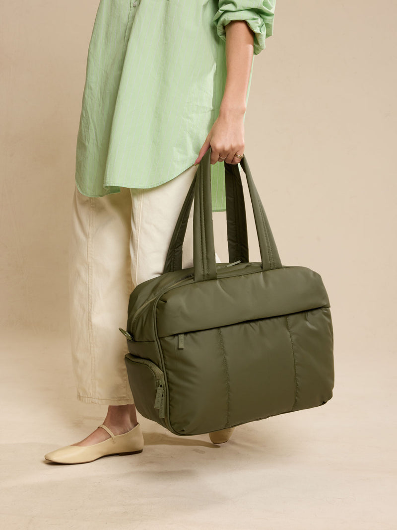 Model holding CALPAK Luka Duffel in dark green Pine