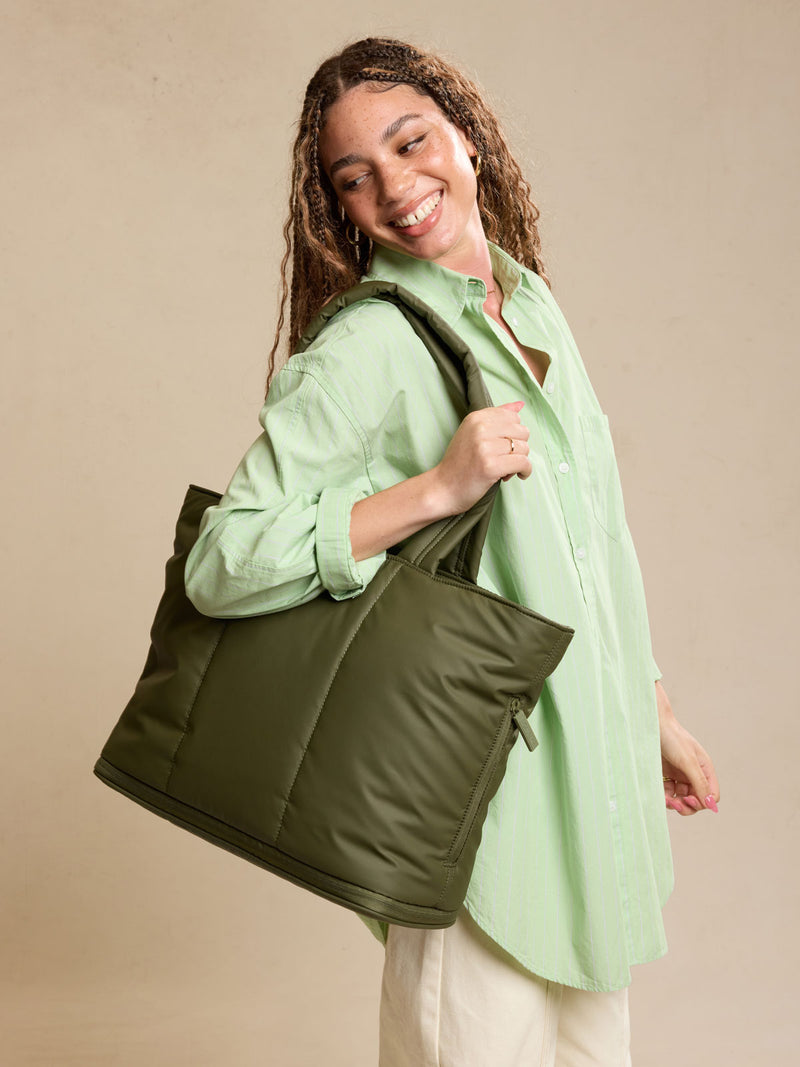 Model wearing CALPAK Luka Expandable Tote bag in dark green