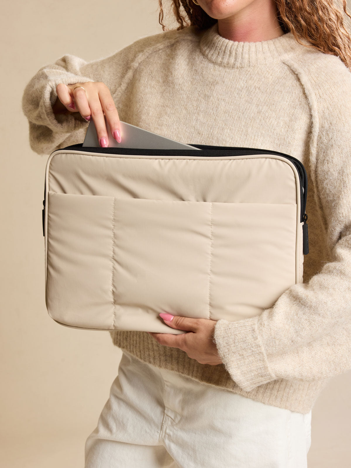 Model holding the CALPAK Luka 17-in Padded Laptop Sleeve in creamy white Oatmeal with puffy exterior back view; ALD2501-OATMEAL