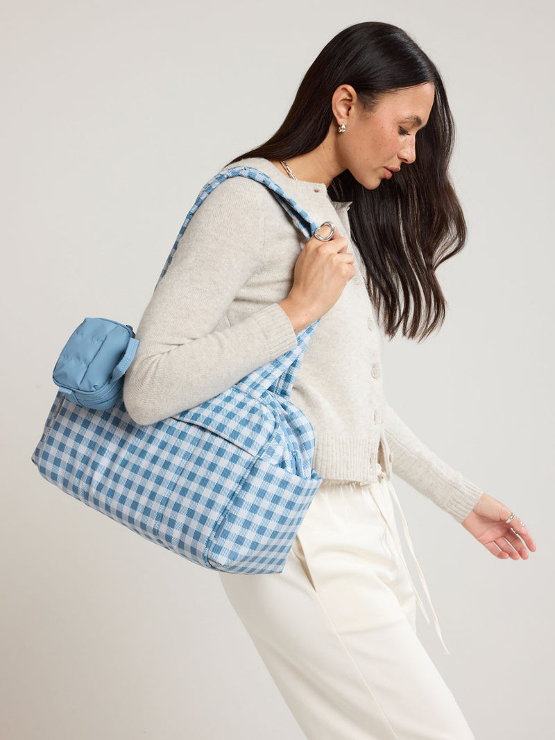Woman wearing the CALPAK Luka Mini Duffel in white and blue gingham print in French Blue Gingham