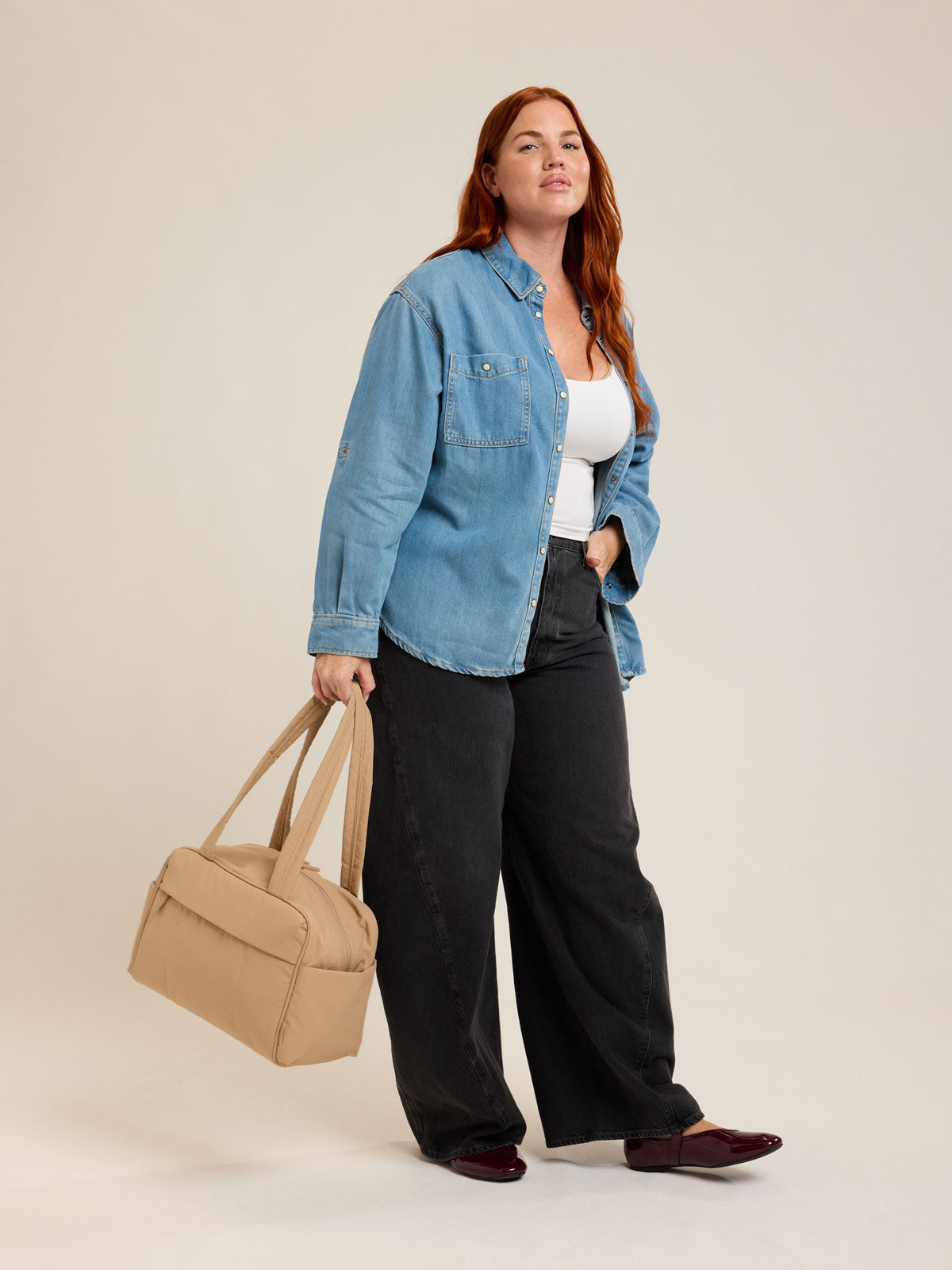 Model with CALPAK Luka Mini Duffel in beige Latte on a white background; DLM2501-LATTE