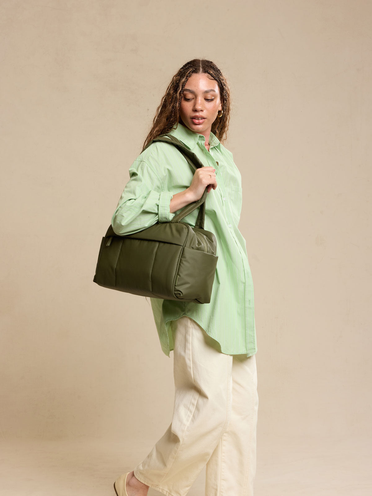 Model wearing CALPAK Luka Mini Duffel in dark green Pine; DLM2501-PINE