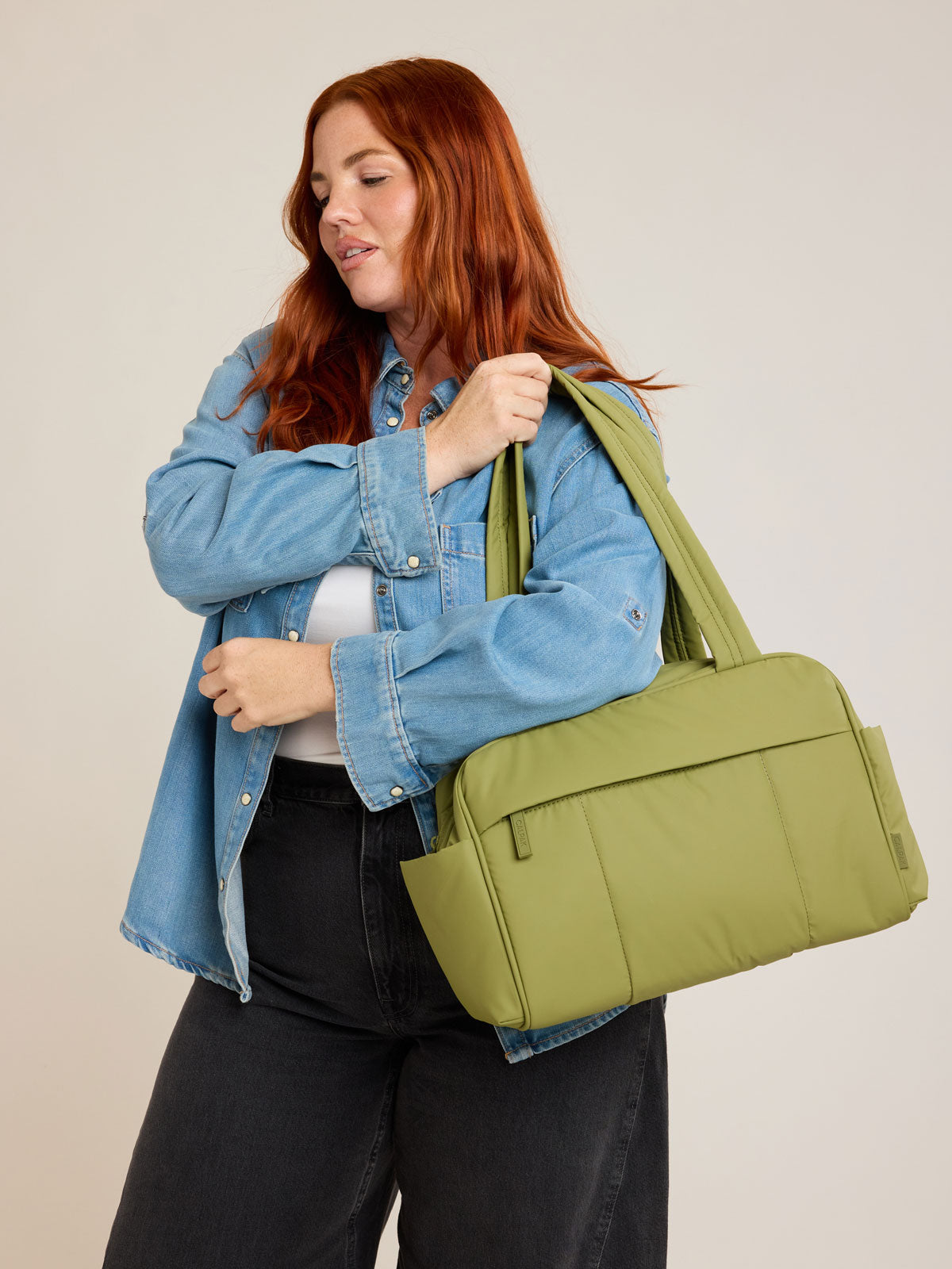 Model with CALPAK Luka Mini Duffel in dark green Pistachio on a white background; DLM2501-PISTACHIO