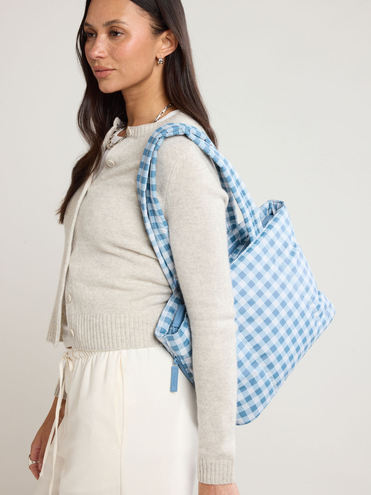 Woman wearing CALPAK Luka Mini Tote in white and blue gingham pattern in French Blue Gingham ; ALM2401-FRENCH-BLUE-GINGHAM