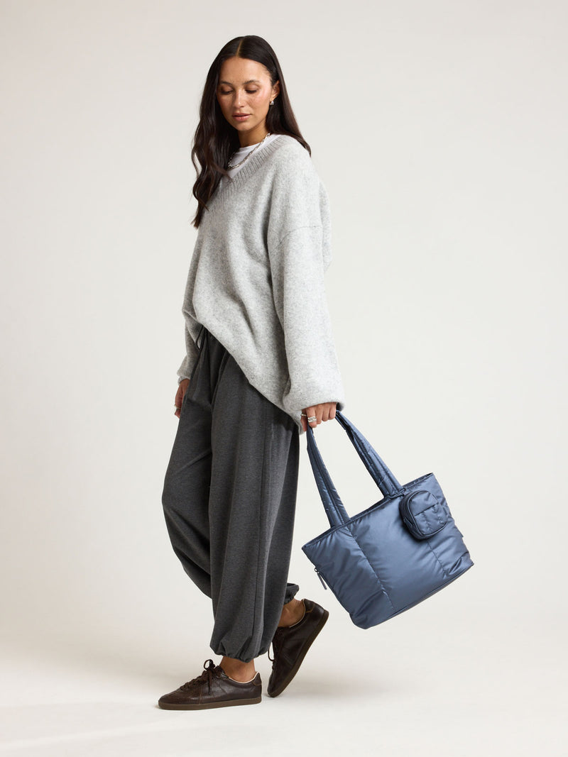 Woman holding CALPAK Luka Mini Tote in metallic dark blue material in Metallic Indigo