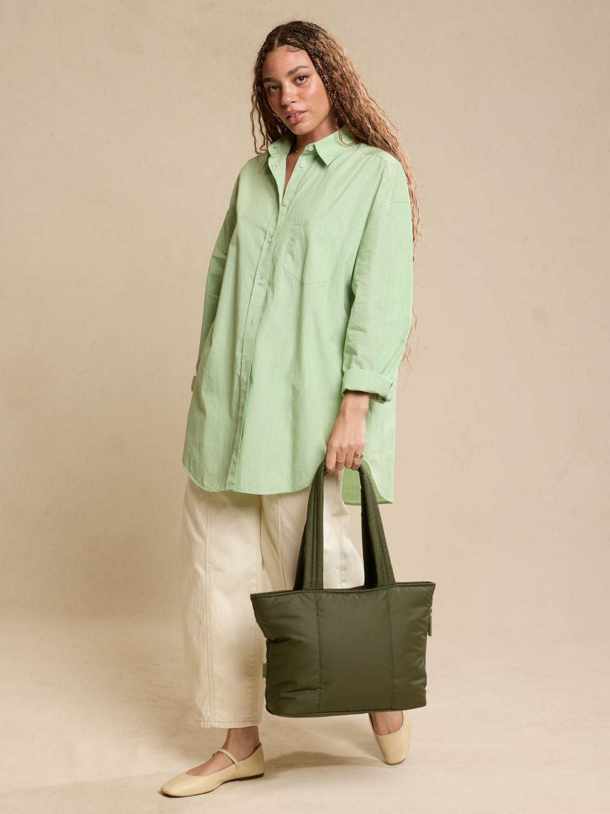 Model holding CALPAK Luka Mini Tote in dark green Pine; ALM2401-PINE