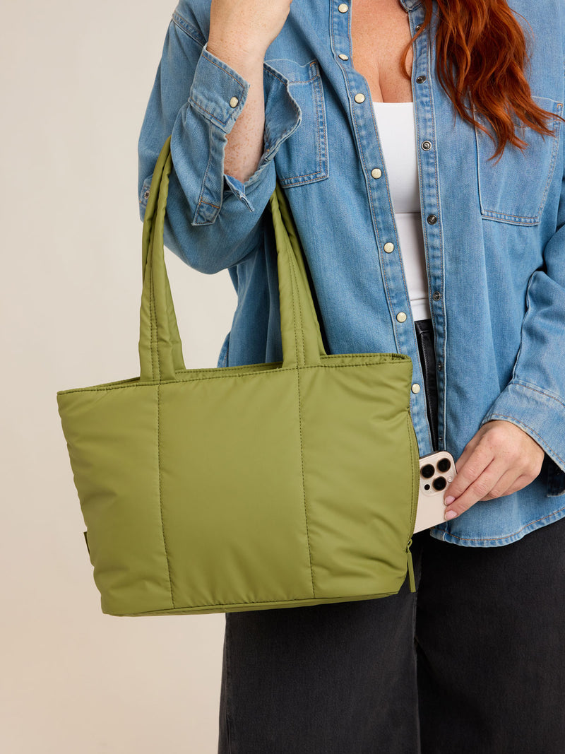Model holding CALPAK Luka Mini Tote in green Pistachio on a white background