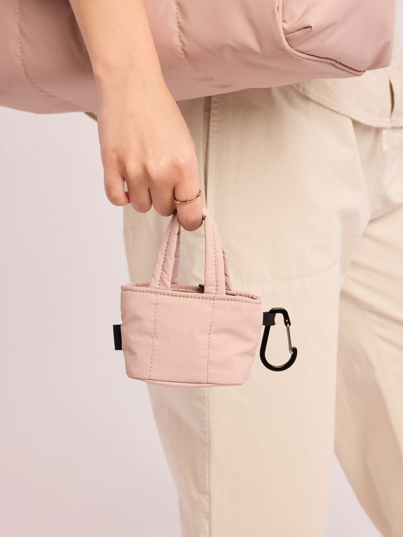 Model holding CALPAK Luka Tote Zip Bag Charm in light pink Rose Quartz  with carabiner