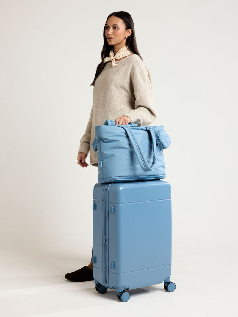 Woman with CALPAK Luka Expandable Tote in light blue French Blue