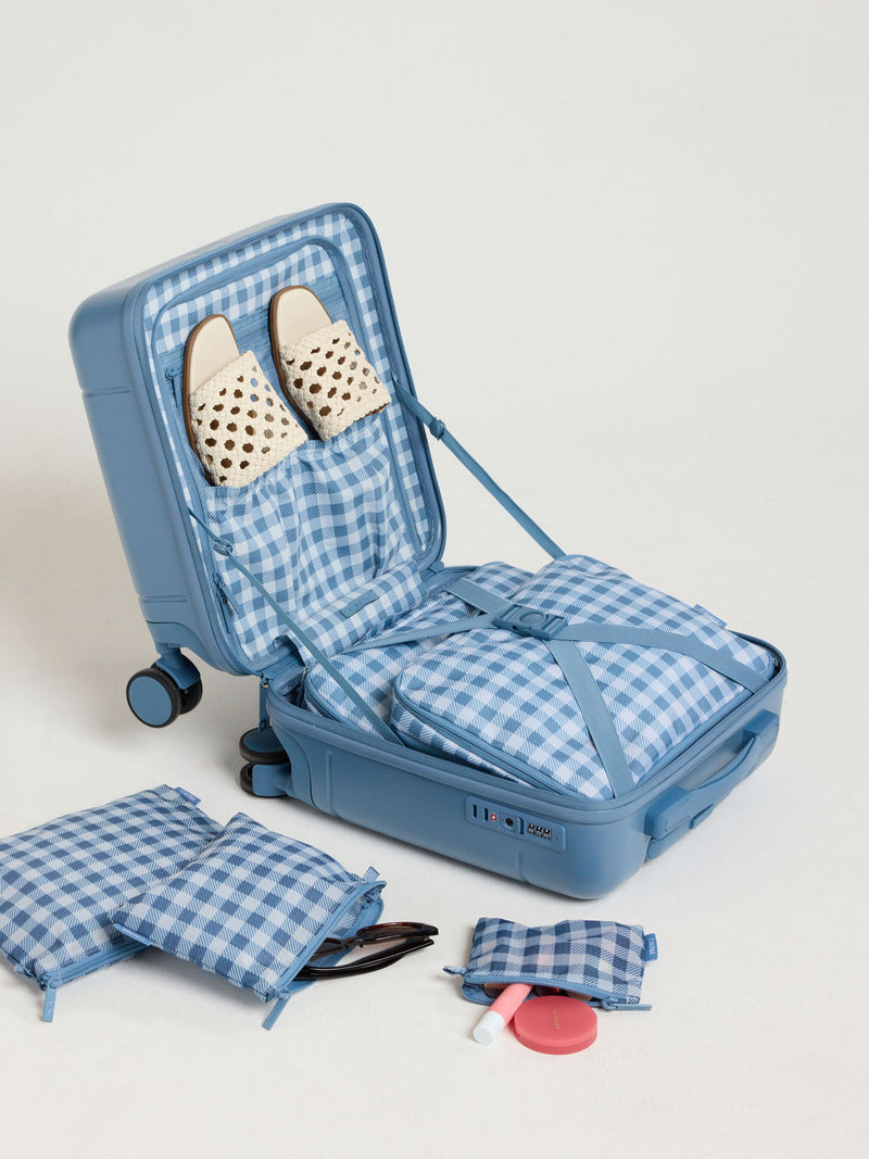 CALPAK Medium Compression Packing Cubes (Set of 2) in white and blue gingham print in French Blue Gingham packed in a suitcase