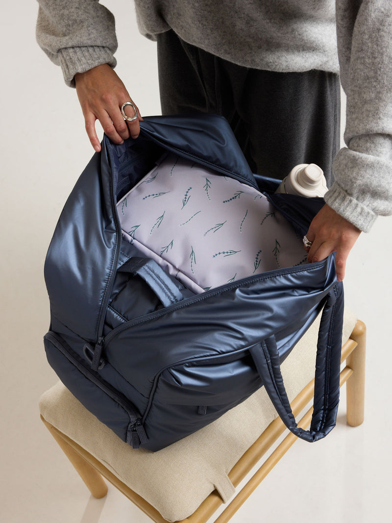 Model packing the CALPAK Medium Compression Packing Cubes (Set of 2) in light purple with lavender print in Lavender Bloom