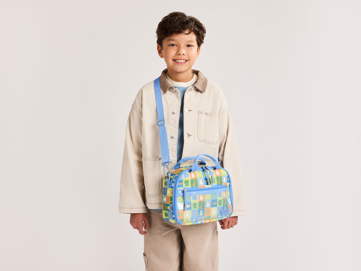Child model wearing blue CALPAK Miffy Insulated Lunch Bag 