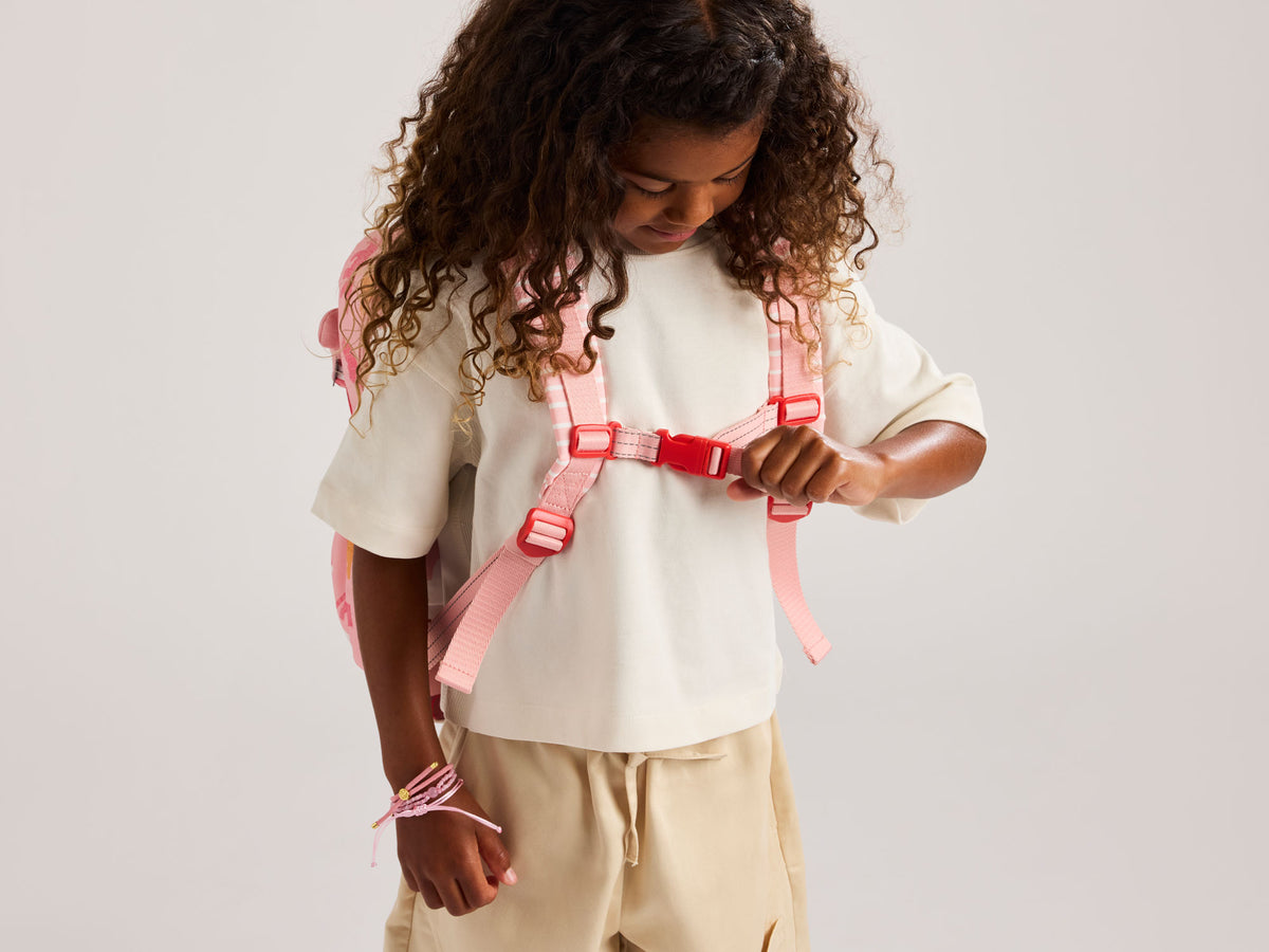Child wearing a pink CALPAK Miffy Kids backpack with a white background
