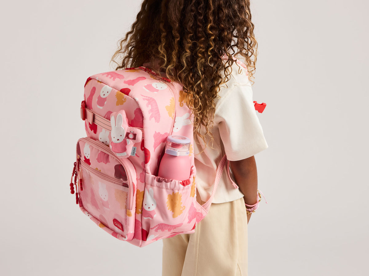 Child model wearing pink CALPAK Miffy Kids Backpack on back with water bottle in side pocket