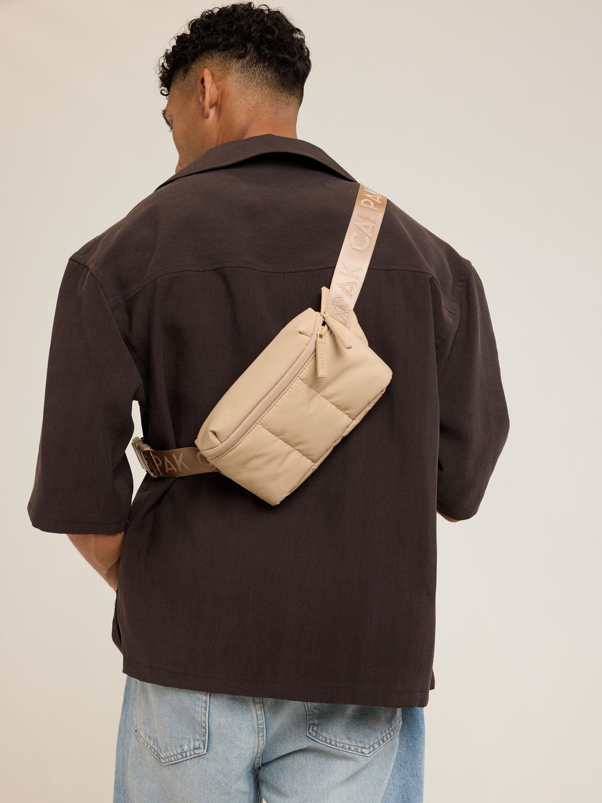 Model wearing CALPAK Luka Mini Belt Bag in beige Latte on white background; BBM2201-LATTE