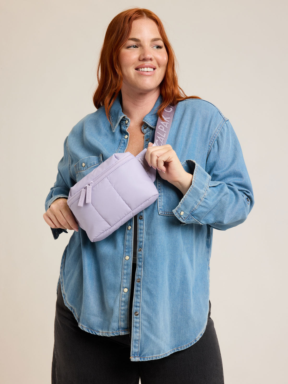 Model wearing CALPAK Luka Mini Belt Bag in light purple Orchid on white background; BBM2201-ORCHID