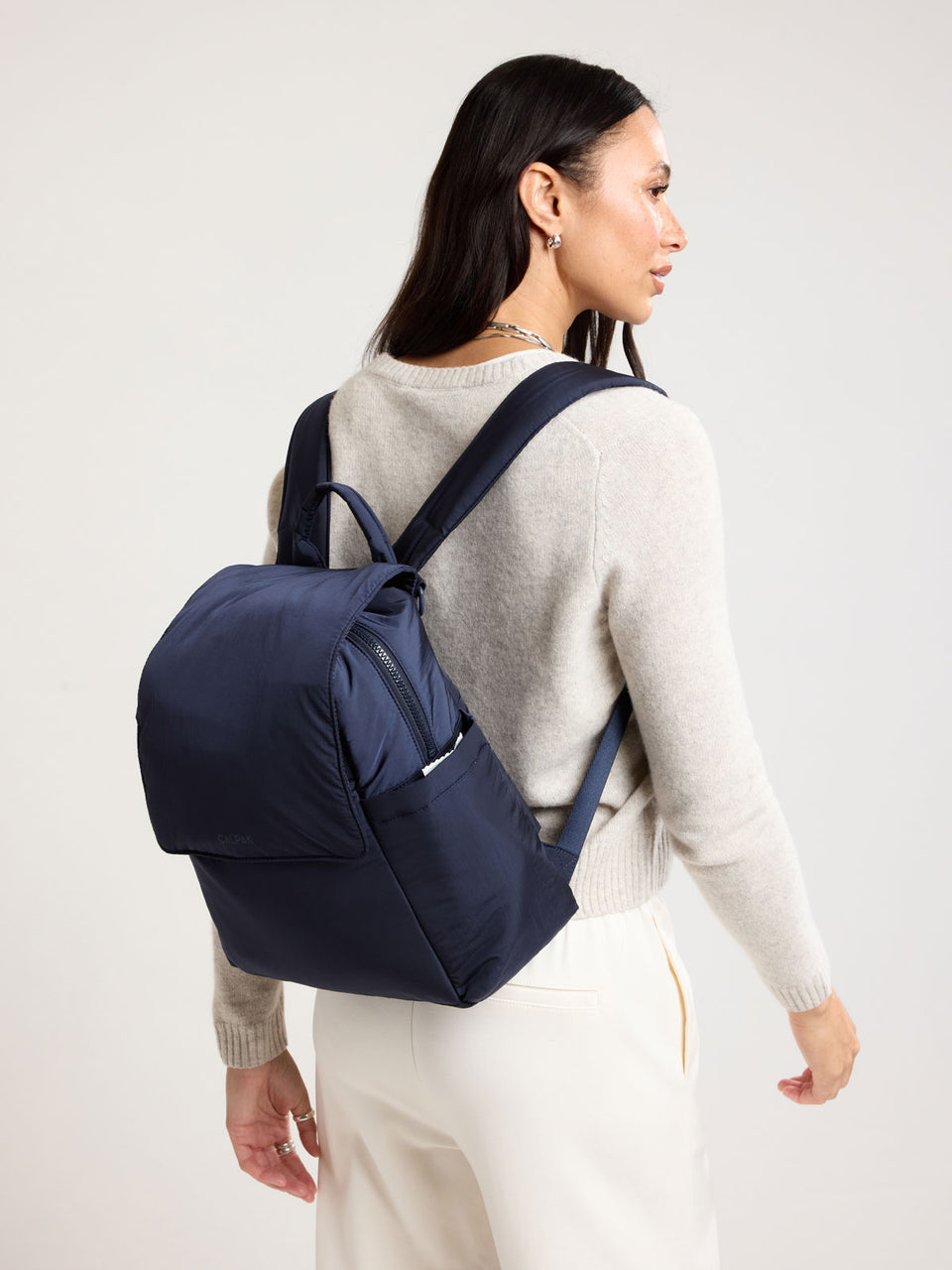 Woman wearing CALPAK Mini Diaper Backpack in blue Navy; BPC2402-NAVY