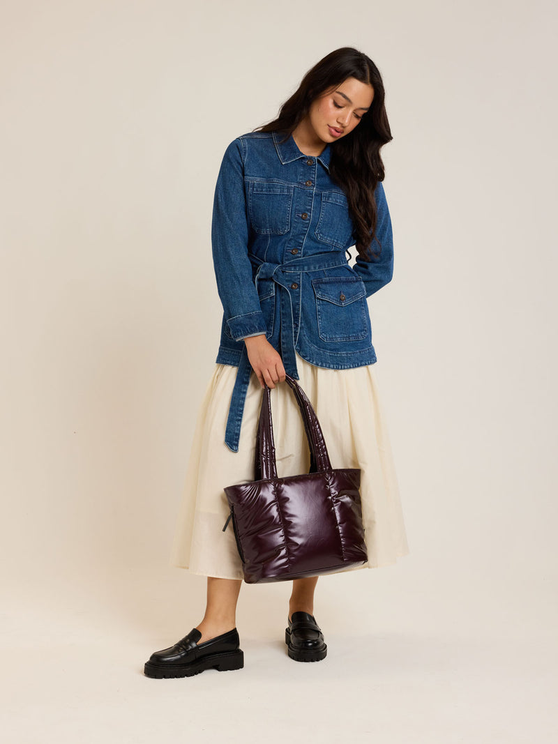 Model carrying the CALPAK Luka Mini Tote in shiny maroon Glazed Dark Cherry on a white background