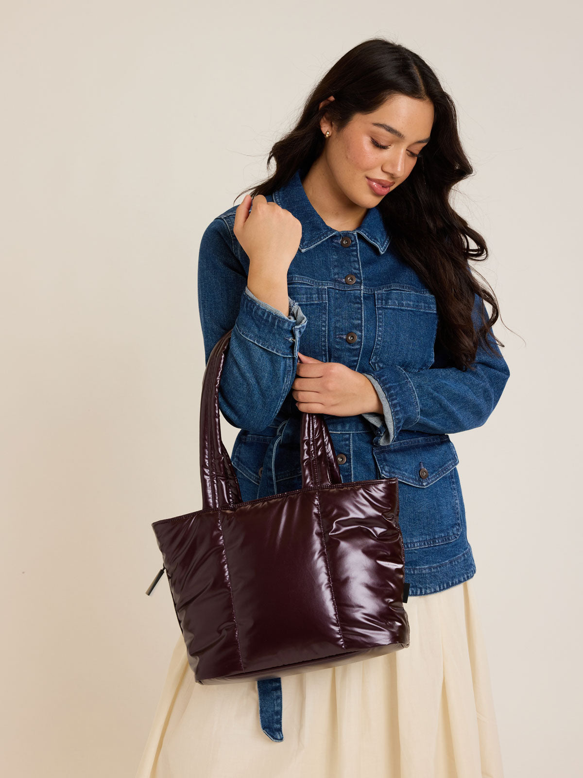 Model with CALPAK Luka Mini Tote in shiny maroon Glazed Dark Cherry on a white background; ALM2401-GLAZED-DARK-CHERRY
