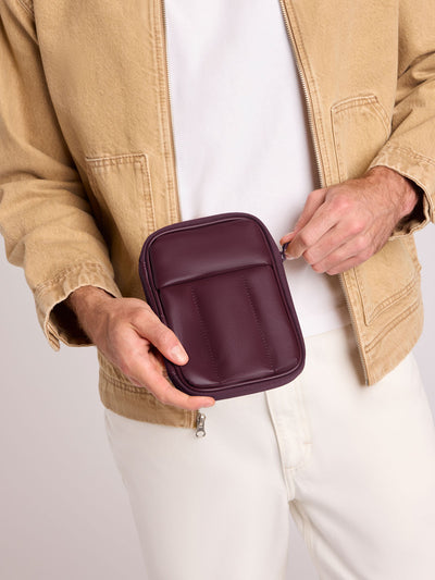 A deep burgundy Dark Cherry CALPAK Luka Zip Passport Wallet in vegan leather with a zippered top and a front pocket, shown on a plain white background; PZW2301-DARK-CHERRY-PU view 2