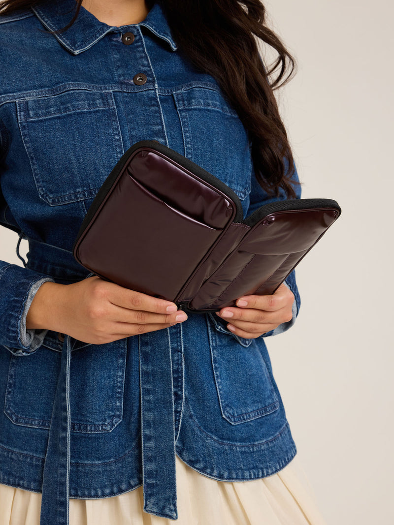 Model with opened CALPAK Luka Zippered Passport Wallet in maroon Glazed Dark Cherry