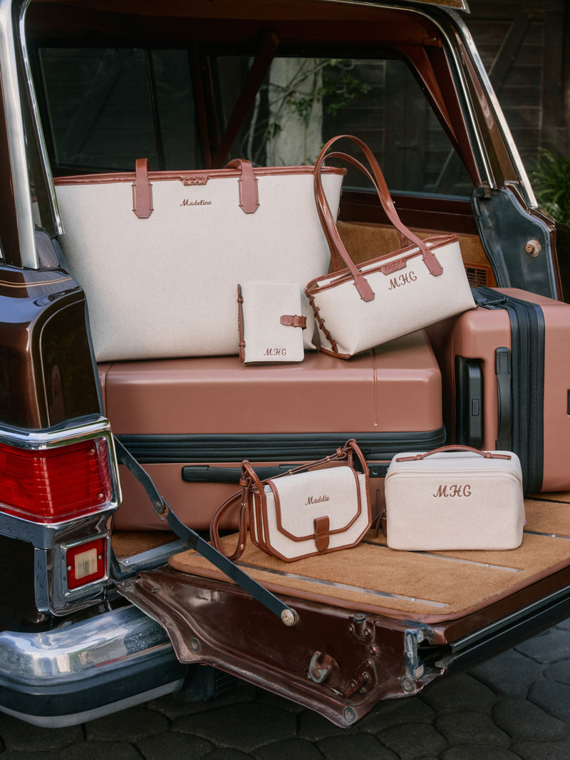 Collection of CALPAK luggage and Colette Collection bags with 'MHC' personalization in a vehicle.
