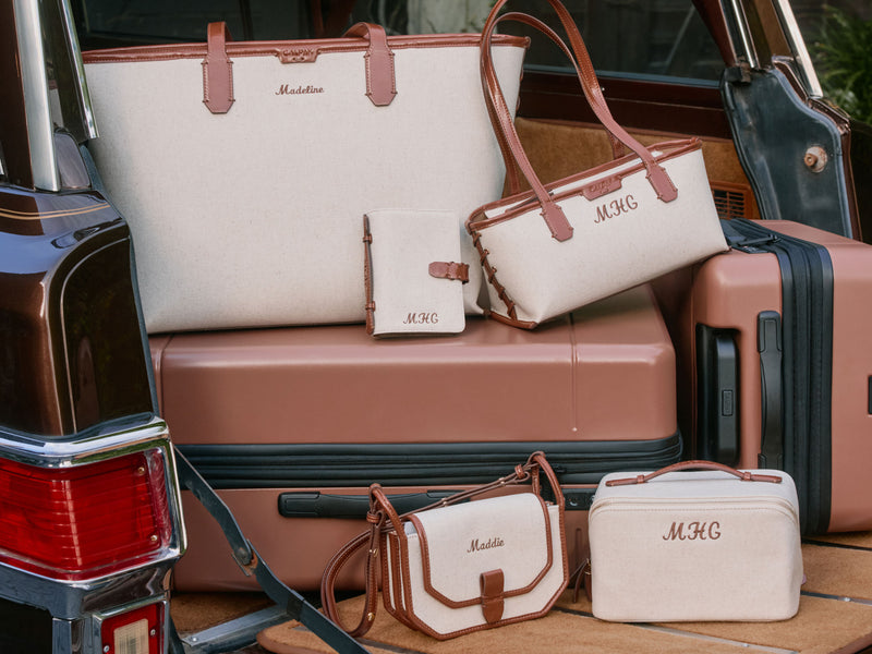 Collection of CALPAK luggage and Colette Collection bags with 'MHC' personalization in a vehicle.