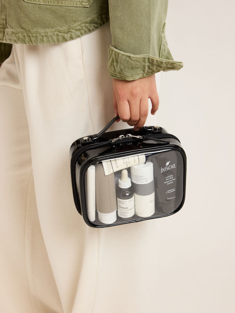Model carrying Side view of CALPAK Small Clear Cosmetic case in Glazed Black