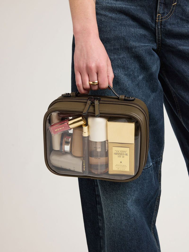 Person holding CALPAK Small Clear Cosmetics Case in brown Mushroom