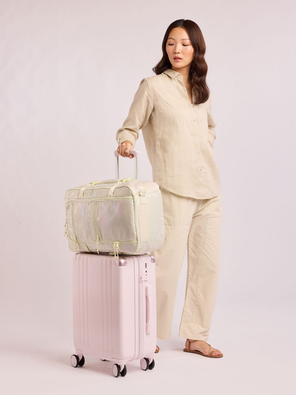 Model with CALPAK Terra 26L Laptop Duffel Backpack with multiple pockets in shiny white Moonbeam on a white background; BPH2201-MOONBEAM
