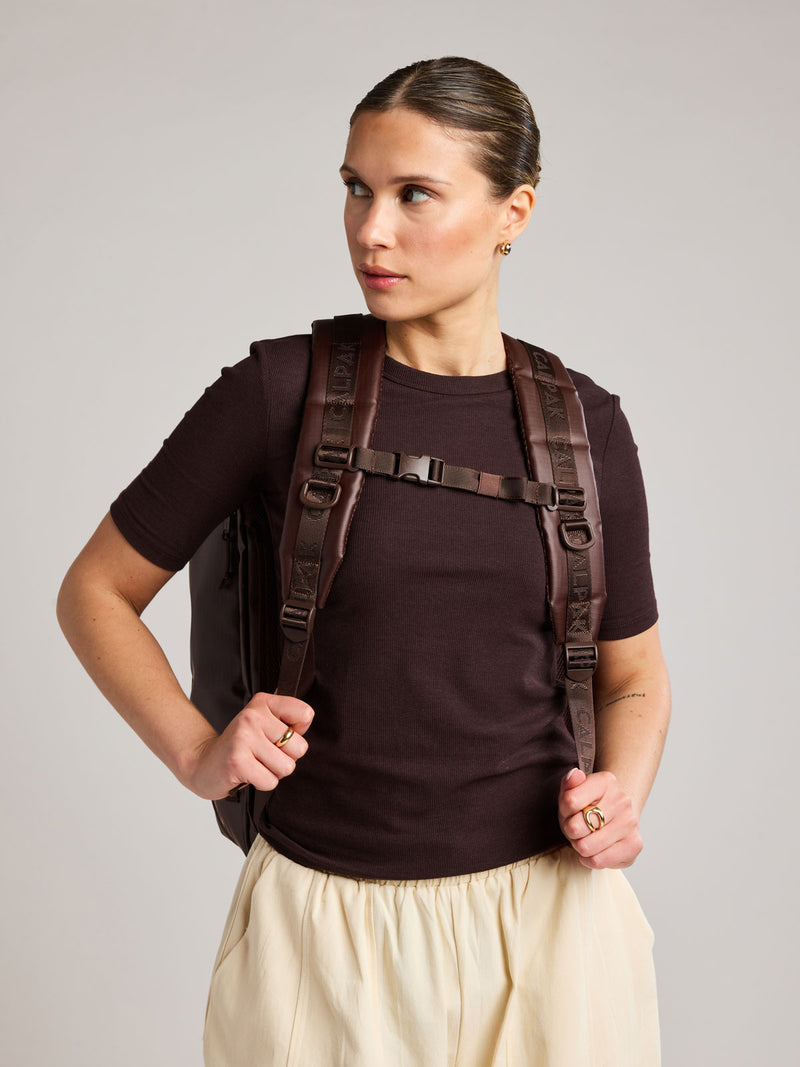 Woman wearing the CALPAK Terra 35L Laptop Backpack Duffel in matte brown Walnut on a white background