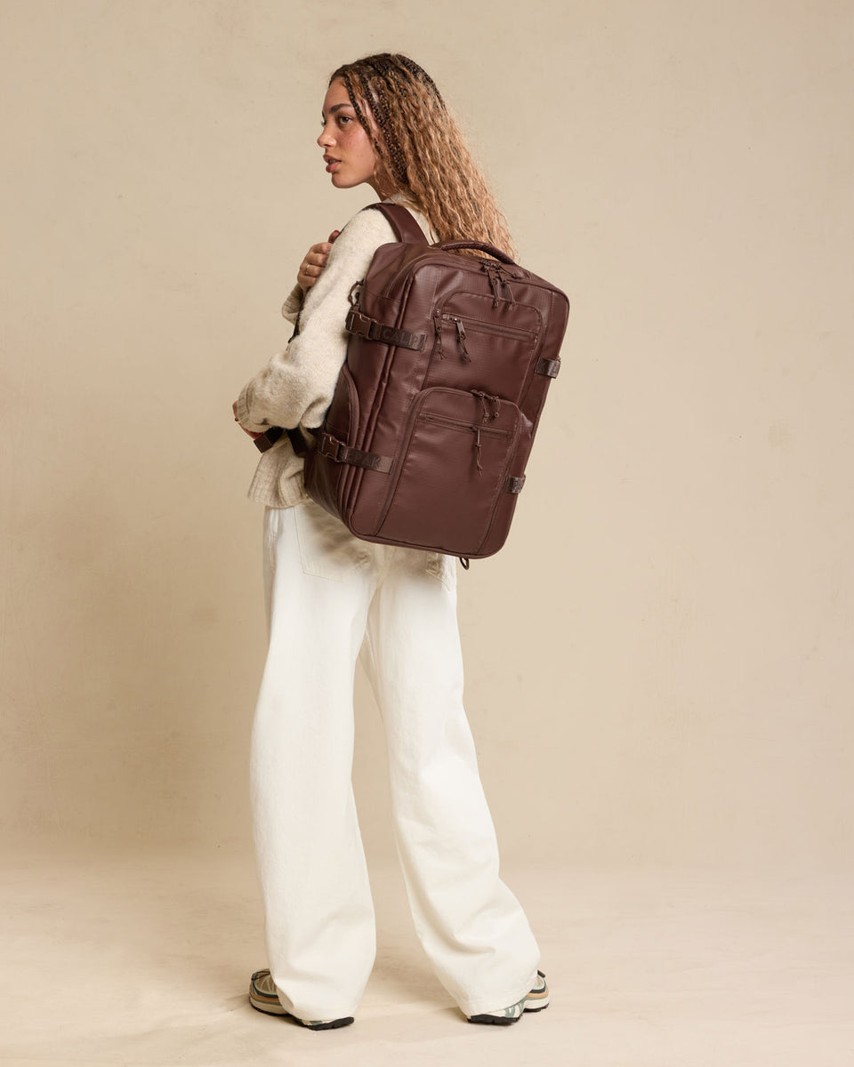 Woman wearing CALPAK Terra 26L Laptop Duffel Backpack in brown Walnut front view;  BPH2201-WALNUT