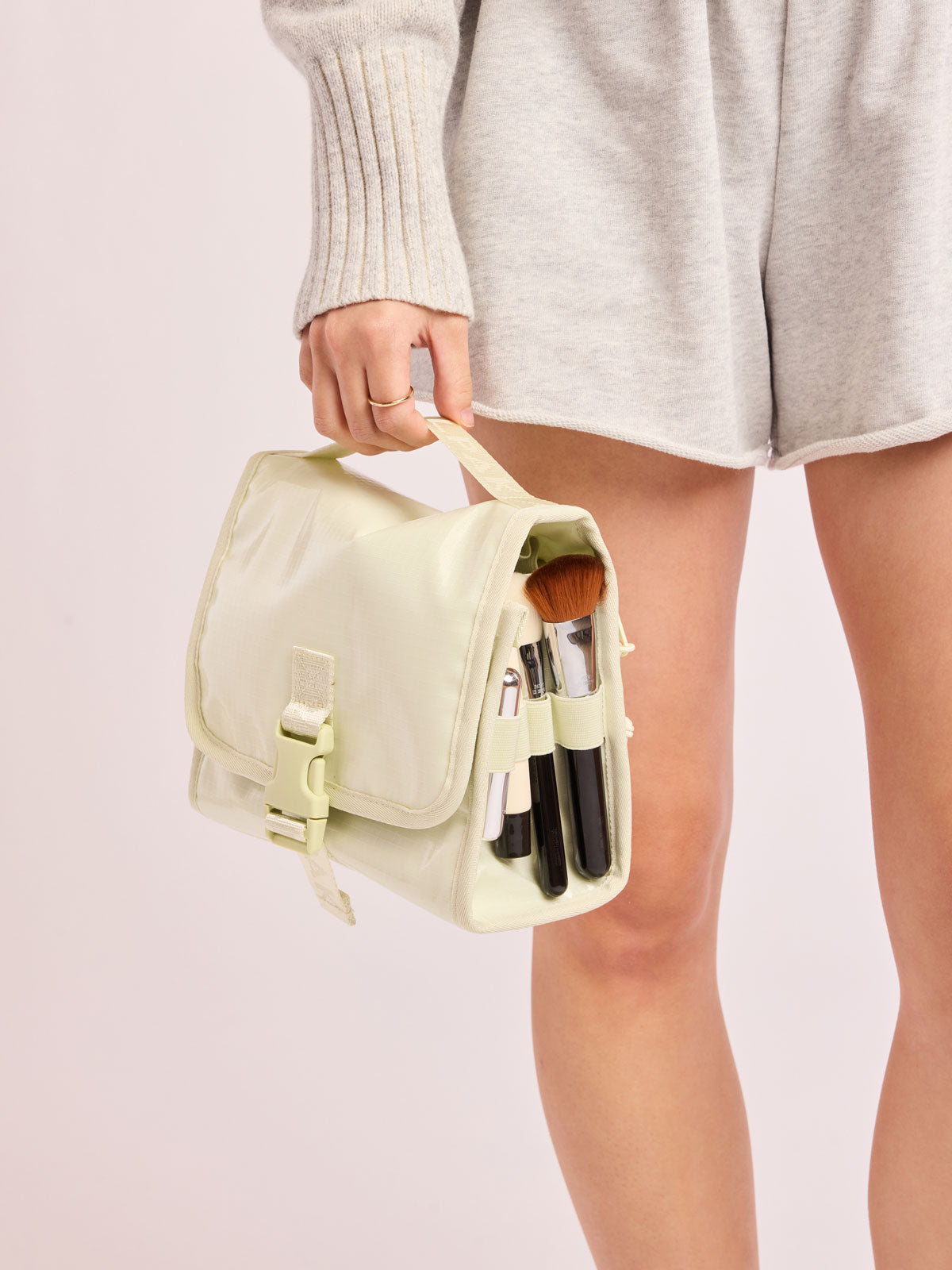 Model holding CALPAK Terra Hanging Toiletry Bag in light green Celadon with front buckle; THY2201-CELADON