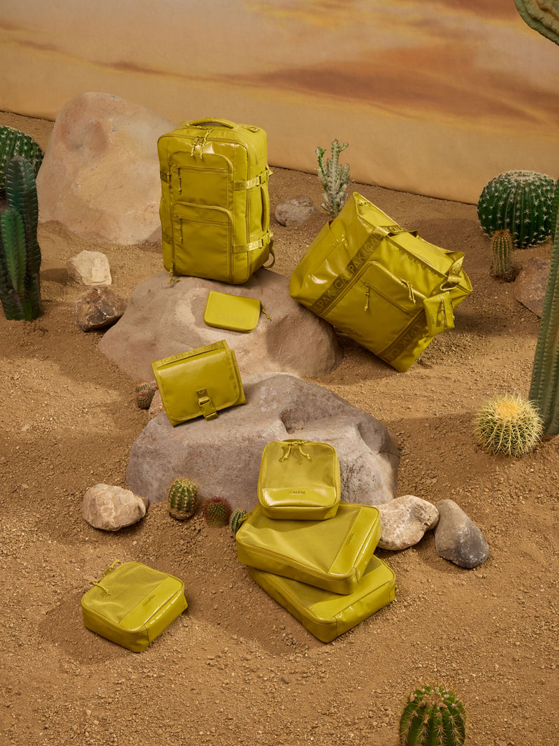 CALPAK Terra 5pc Packing Cube Set and other Terra items in yellow green Wasabi in a desert  themed background