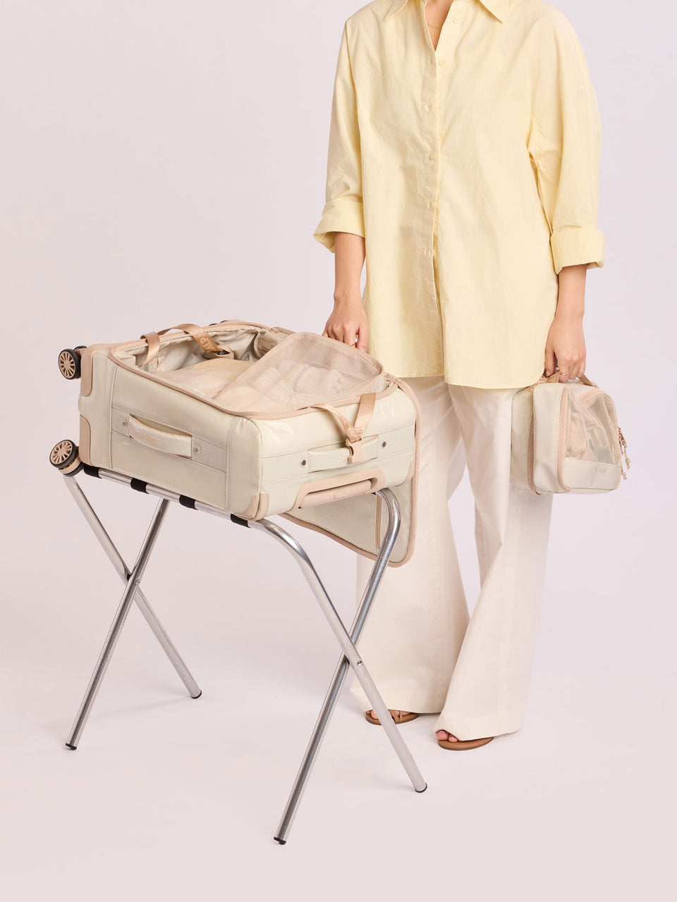 Model packing luggage with the CALPAK Terra 5-Piece Packing Cube Set in off-white beige White Sands with two small cubes, two medium cubes, and one large mesh cube with zippers and mesh; PCT2601-WHITE-SANDS