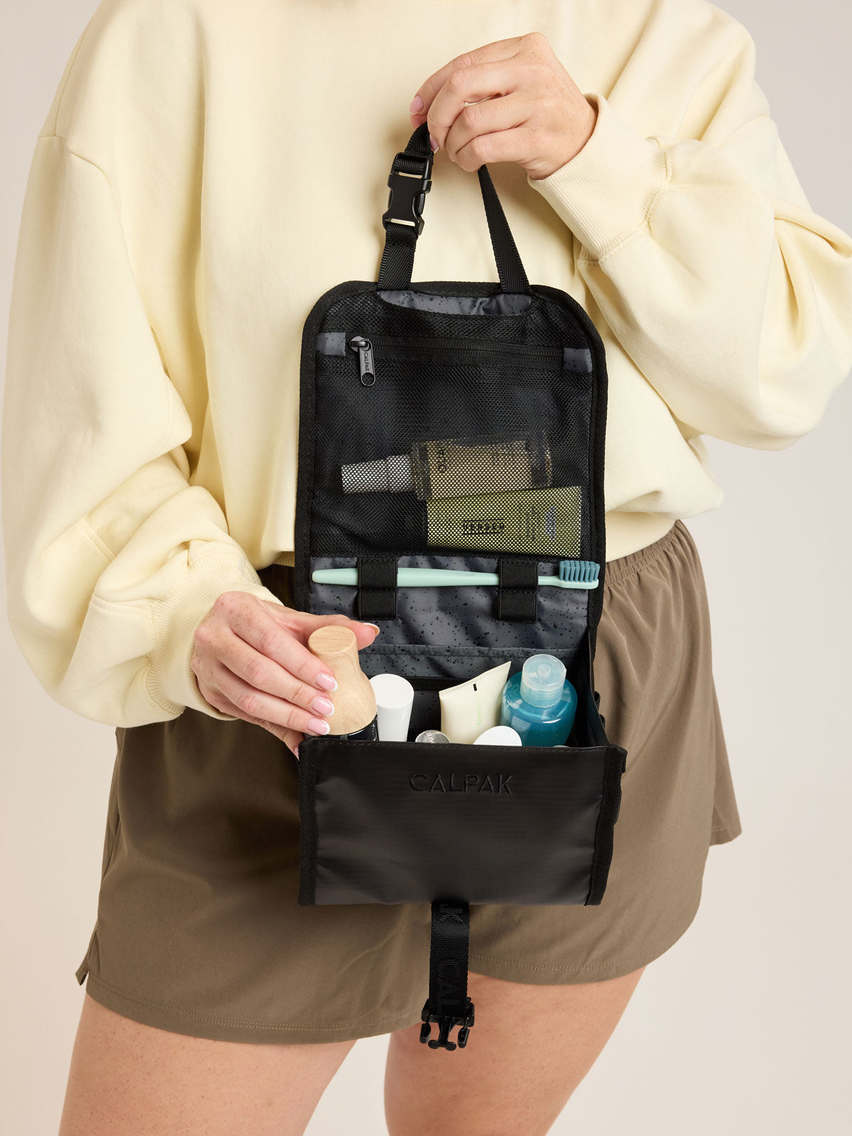 Model with CALPAK Terra Hanging Toiletry Bag in black Matte Obsidian front view; THY2201-MATTE-OBSIDIAN