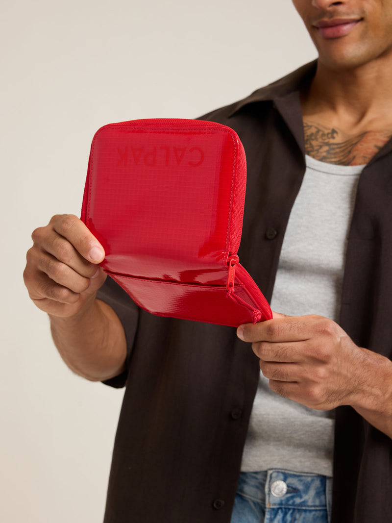 Model with CALPAK Terra Zip Passport Wallet in red Flame front
