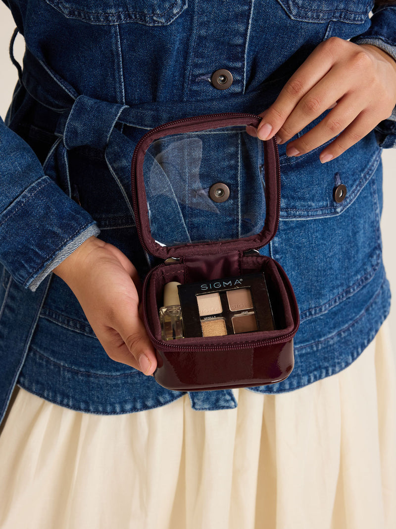 Model with CALPAK Tiny Clear Cosmetics Case in maroon Dark Cherry with makeup inside