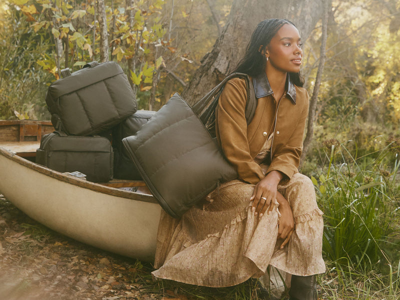 Woman sitting by a canoe with camping gear and Luka Collection in Mushroom in a forest setting