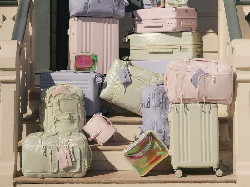 Collection of Ambeur pastel-colored suitcases on a staircase with Terra bags