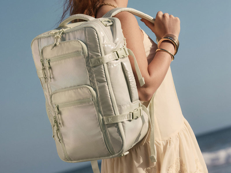 Person wearing a light green Celadon Terra 26L Laptop Backpack against a blue sky background