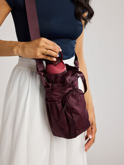 Dark burgundy CALPAK Water Bottle Holder with top handles, drawstring top, front zippered pocket, and a detachable shoulder strap; AWH2101-DARK-CHERRY view 2