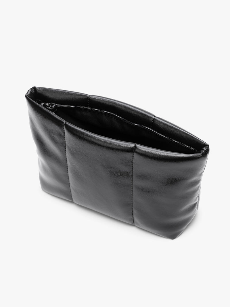 Opened zipper of CALPAK black vegan leather pouch bag with a structured rectangular shape and vertical stitched panel details, shown against a plain white background