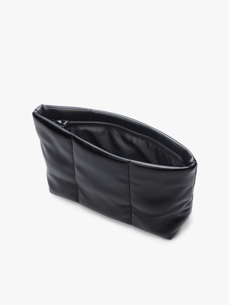 Opened zipper of a CALPAK Luka 1 quart black vegan leather pouch bag with a quilted, padded design and a small black brand tag on the right side, shown against a plain white background