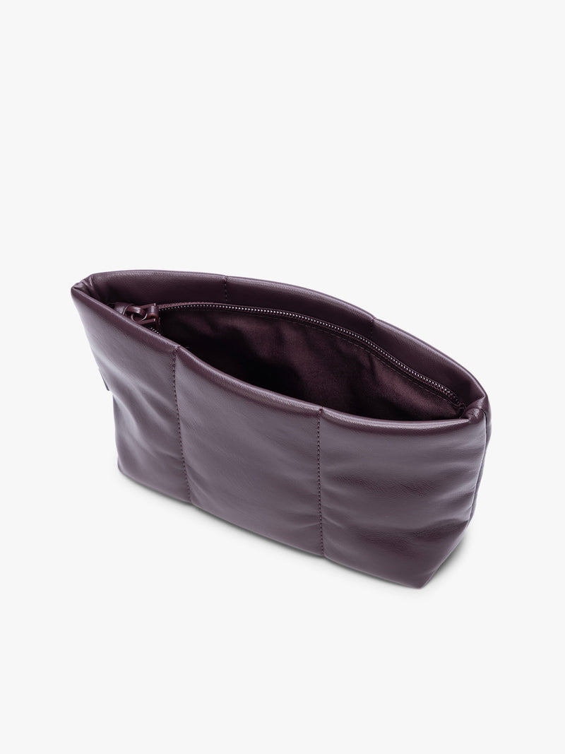 Opened zipper of a CALPAK Luka 1 quart deep plum Dark Cherry vegan leather pouch bag with a quilted, padded design and a small brand tag on the right side, shown against a plain white background